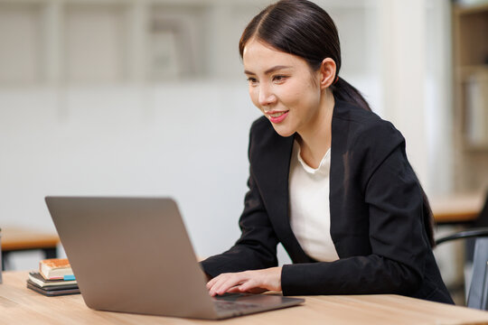 Asian Business woman using calculator and laptop for doing math finance on an office desk, tax, report, accounting, statistics, and analytical research concept

