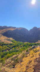 Fototapeta premium Autumn mountain valley with dry soil, golden foliage, and rugged peaks under clear blue sky — a vivid seasonal contrast. 📍Hazarani, Hawraman