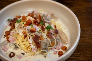 Spaghetti Carbonara with ham and bacon served on a white plate. Soft Focus.