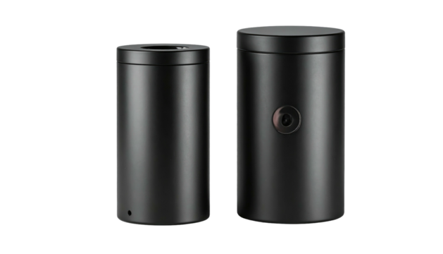 Two dark cylindrical objects, one with a small dot, against a solid black background with dramatic lighting
