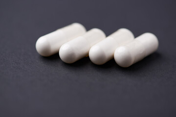 HMB capsules on dark background. Soft focus. Close up. Copy space.	