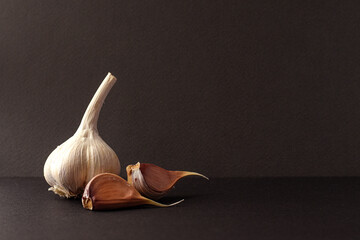 Garlic Bulbs Composition on Black Surface. Close-up of garlic bulbs arranged artistically on black...