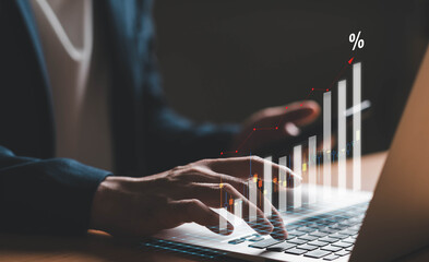 A modern business concept image illustrating economic growth, inflation, and financial data analysis. The photo shows a close-up of a person typing on a laptop keyboard with a holographic bar chart