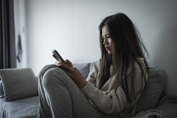 Young Asian woman sitting  on the sofa at home, feeling sad tired and worried suffering depression in mental health. in concept of depression anxiety and insomnia