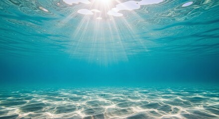 Underwater view, sun rays, clear blue ocean, sandy sea floor