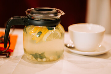 Refreshing herbal drink served in a clear jar beside a white cup and a spoon
