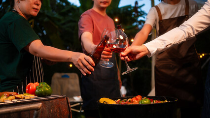 An Asian woman with friends grilling BBQ skewers, corn, and sausages outdoors. They toast with wine amid glowing string lights, creating a joyful and warm evening barbecue atmosphere
