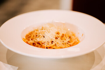 Delicious pasta topped with cheese served in a white bowl at a casual dining spot