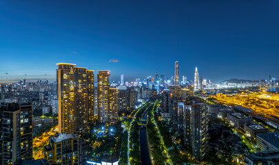 Obraz premium Panoramic view of Shenzhen modern city skyline at night with residential buildings and a green parkway below.