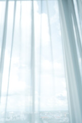 Sheer curtains draped over window, allowing soft light. Serene atmosphere invites relaxation.