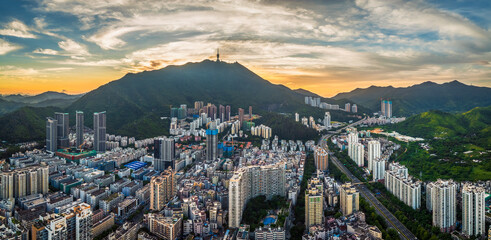 Aerial panorama of the city nestled among green mountains with a communication tower on the peak at...
