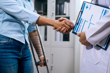 An Asian female patient with multiple injuries shakes hands with a male doctor in a clinic, showing gratitude and trust after treatment. Medical recovery and patient care atmosphere