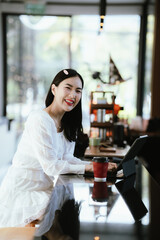 A woman relaxing in a modern café, enjoying a hot drink while sitting at the counter with a tablet nearby, looking thoughtful and content.