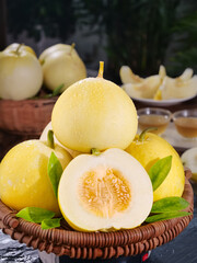 Golden Sweet Honeydew Melons in Wicker Basket with Fresh Green Leaves