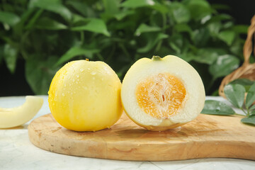 Golden Sweet Melon Halves on Wooden Board with Natural Green Background
