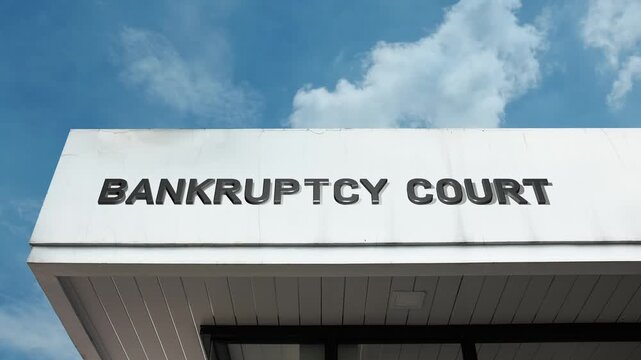 Bankruptcy Court word sign prominently mounted on a government or judicial building's facade against a clear blue sky, representing legal proceedings for financial distress and economic restructuring