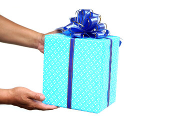 Hands holding a beautifully wrapped gift box with blue polka dot paper and a shiny blue ribbon bow on white background. Concept of celebration, giving, birthday, and special occasion surprise.