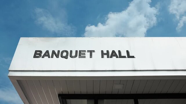 Banquet Hall word sign displayed on the exterior of a reception or event building beneath a bright blue sky, indicating a large venue for dinners, celebrations, and formal gatherings