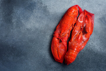 Frozen lobster in ice glaze. Seafood delivery. On gray concrete background, top view.