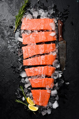 Fresh raw salmon fillet on ice. Fish steak on black stone background. Top view.