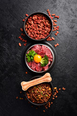 Dog food: dry pelleted food and a bowl of fresh meat with vegetables and egg yolk. Top view.