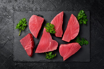 Raw fresh tuna fish steaks set. On black slate background. Close up, Top view.