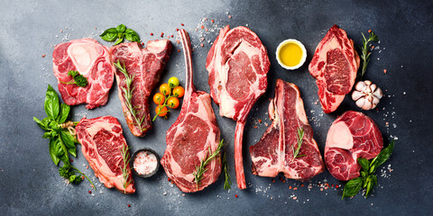 Variety of raw beef meat Prime steaks for grilling with seasoning: Tomahawk steak, Ribeye, T-bone and Ossobuco steak. Meat background.