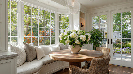 Fototapeta premium Light-Filled Interior: A cozy breakfast nook bathed in natural light, showcasing a round wooden table adorned with a vibrant floral arrangement.