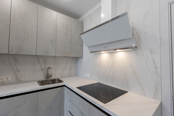 Brand new fitted kitchen with white cabinet and fully marble tiled walls