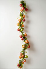 beautifully arranged christmas garland adorned with colorful ornaments rests against pristine white wall