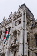 Fototapeta premium Flags on the beautiful old building of the Hungarian Parliament in neo-Gothic style