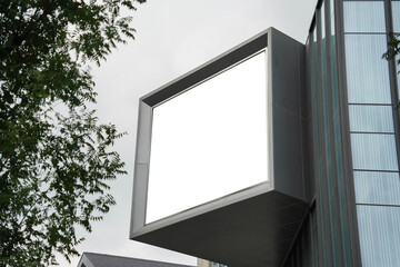 A mockup of a blank white billboard framed by a modern building facade, ideal for advertising