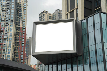 A mockup of a blank white billboard framed by a modern building facade, ideal for advertising