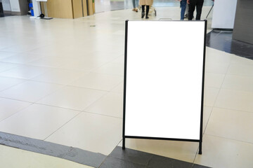 Blank white outdoor advertising stand sandwich board mock up template. Clear street signage board placed by an outdoor dinning area of a restaurant.