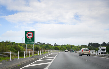 110 km/h speed limit road sign at Kapiti Expressway. Cars and Motorhome travelling on the expressway. New Zealand;