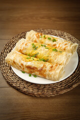 Pan-fried egg and ham dumplings with chives on rustic wooden table - homemade Asian pastry preparation