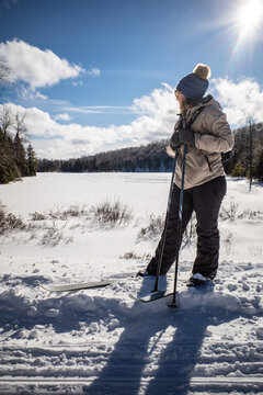 Female cross country skier looks across a snow covered lake