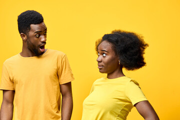 Fototapeta premium Two surprised models in yellow clothing expressing emotion against a vibrant yellow background, showcasing joy and surprise in a playful, energetic concept