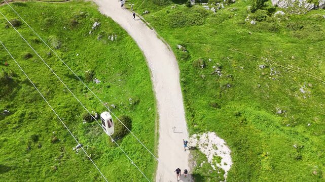 14 july 2024, Italy. Drone flight above sassolungo cable car, telecabin force del sassolungo, coffin lift, during summer. Hikers are walking on a hiking trail. Vintage cable car from the 60's. Dolomit
