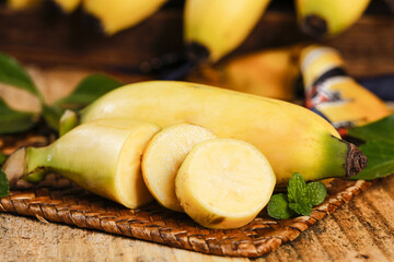 Fresh Ripe Bananas Sliced on Wicker Basket with Mint Leaves on Rustic Wood Background