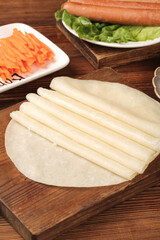 Handmade Rolled Pancakes with Shredded Filling and Sausages on Wooden Board