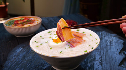 Hand-rolled noodles with bacon and egg in chopsticks - Asian cuisine dish
