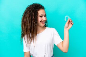 Young Arab woman holding invisible braces isolated on blue background with happy expression
