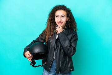 Young Arab woman with a motorcycle helmet isolated on blue background and looking up