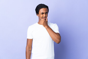 Young African American man with braids man isolated on purple background having doubts