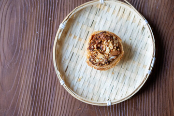 Close-Up of Traditional Portuguese Pistachio Nata Dessert in a Wicker Plate on a Brown Table
