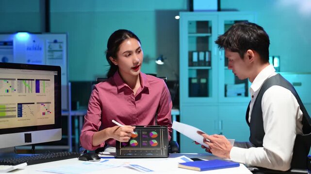 Asian coworkers discussing analytics on tablet in modern office, teamwork, data visualization, business strategy, and corporate collaboration concept. - Powered by Adobe