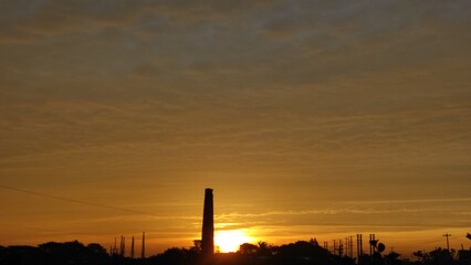 City sunset with an urban skyline and dark silhouette of buildings against a dusk sky filled with clouds