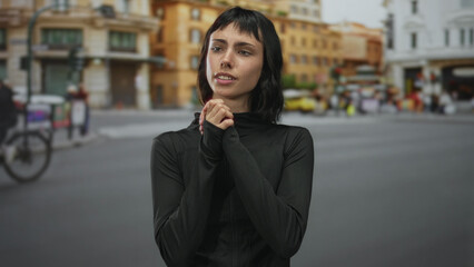 Fototapeta premium Young woman in black sportswear uses fingers to fasten jacket zipper on urban street at sunrise; confidence.