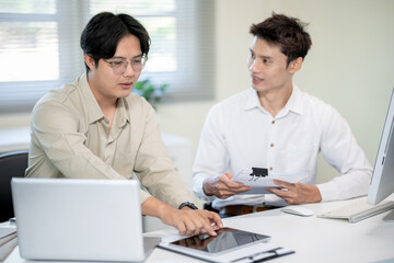 Obraz premium Two male office workers are discussing work in the office.